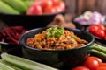 Sweet pork in a black bowl, complete with cucumbers, long beans, tomatoes, and side dishes