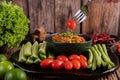 Sweet pork in a black bowl, complete with cucumbers, long beans, tomatoes, and side dishes