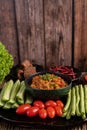 Sweet pork in a black bowl, complete with cucumbers, long beans, tomatoes, and side dishes