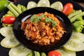 Sweet pork in a black bowl, complete with cucumbers, long beans, tomatoes, and side dishes