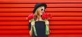 Sweet portrait of beautiful smiling woman with bouquet of red rose flowers in black round hat on background Royalty Free Stock Photo