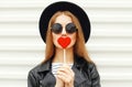 sweet portrait young woman covering her lips with red heart shaped lollipop