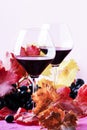 Sweet portuguese red wine in large glasses, autumn still life with red and yellow leaves on pink background, selective focus Royalty Free Stock Photo