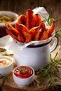 Sweet potato french fries seasoned herbs and sea salt in enamel mug and spicy dips on a wooden table Royalty Free Stock Photo