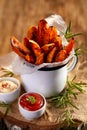 Sweet potato french fries seasoned herbs and sea salt in enamel mug and spicy dips on a wooden table Royalty Free Stock Photo