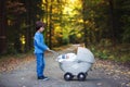 Sweet preschool boy pushing his little newborn baby boy, sleeping in old retro stroller in forest Royalty Free Stock Photo