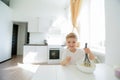 Sweet preschool child, helping his mom in the kitchen, making pancakes in the morning, happy childhood