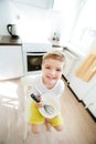 Sweet preschool child, helping his mom in the kitchen, making pancakes in the morning, happy childhood