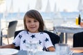 Sweet preshcool child, sitting in beach restaurant, waiting for the food to arrive Royalty Free Stock Photo