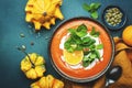 Sweet pumpkin soup puree with cream, orange and mint. Winter or autumn healthy vegetarian comfort slow food. Soup bowl on green