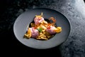 Sweet ravioli with cherries and pink ice cream served in a black plate on a dark marble background. Restaurant food. Italian