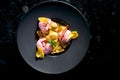 Sweet ravioli with cherries and pink ice cream served in a black plate on a dark marble background. Restaurant food. Italian