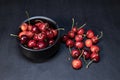 Sweet red cherries piled up in a black ceramic bowl on black background. Top view. Fruit Background. Selective focus Royalty Free Stock Photo