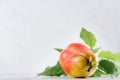 Sweet ripe fresh orange pear with water drops, green leaves, spotted lay on white wood table, closeup, blur.