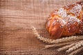 Sweet roll wheat ears on oak wooden board food and Royalty Free Stock Photo