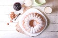 Sweet round fruity homemade pie with hole, on a white dish on a wooden table served with a cup of milk. Piece of cake