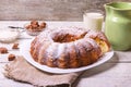 Sweet round fruity homemade pie with hole, on a white dish on a wooden table served with a cup of milk. Piece of cake