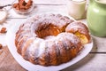 Sweet round fruity homemade pie with hole, on a white dish on a wooden table served with a cup of milk. Piece of cake