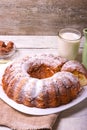 Sweet round fruity homemade pie with hole, on a white dish on a wooden table served with a cup of milk. Piece of cake