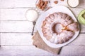 Sweet round fruity homemade pie with hole, on a white dish on a wooden table served with a cup of milk. Piece of cake