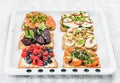 Sweet and savory breakfast toasts variety. Sandwiches with fruit, vegetables, eggs, smoked salmon on white baking tray