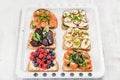 Sweet and savory breakfast toasts variety. Sandwiches with fruit, vegetables, eggs, smoked salmon on white baking tray