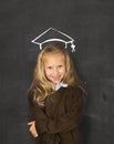 Sweet schoolgirl on blackboard with with chalk sketch drawing of graduation hat smiling happy