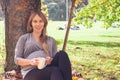 Sweet shot of attractive young woman expecting child sitting under tree, enjoying happy moment of her pregnancy, relaxing in open Royalty Free Stock Photo