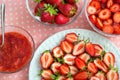 Sweet sliced strawberries on a plate, strawberry jam in a glass bowl, and other sweet berries
