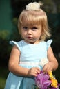 Sweet smiling little girl with long blond hair, sitting on grass in summer park, closeup outdoor portrait. Royalty Free Stock Photo