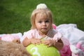 Sweet smiling little girl with long blond hair, sitting on grass in summer park, closeup outdoor portrait. Royalty Free Stock Photo