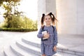 Sweet smiling young child girl 5-6 year old wear checkered black and white dress and backpack holding books stand outdoors close u