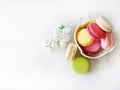 Colorful macarons in a cup on a lace fabric with white roses