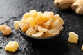 Sweet and spicy candied ginger in black bowl on dark stone background