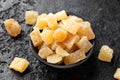 Sweet and spicy candied ginger in black bowl on dark stone background