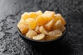 Sweet and spicy candied ginger in black bowl on dark stone background