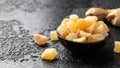 Sweet and spicy candied ginger in black bowl on dark stone background