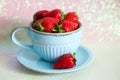 Sweet strawberries in a light blue ceramic Cup and saucer on a shiny background, side view Royalty Free Stock Photo