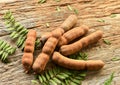 Sweet tamarind pods with leaves on rustic wood background