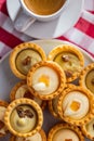 Sweet tarlets. Tasty mini tarts. Mini pie with cream and coffee cup on kitchen table. Top view