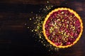 Sweet tart with raspberries, cherries, red currants with pistachios, powdered sugar on dark wooden background. Copyspace Royalty Free Stock Photo