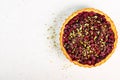 Sweet tart with raspberries, cherries, red currants with pistachios, powdered sugar on white concrete background Royalty Free Stock Photo