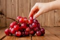 Sweet tasty grapes in graceful woman`s hand on wooden background, copy space