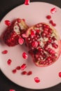 Sweet tasty sour pomegranate seeds flying over pink plate with peeled fruit
