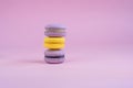 Tasty violet and yellow french macaron cakes on yellow background.