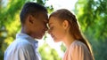 Sweet teenage couple touching foreheads at sunny day park, first relationship