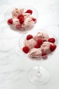 Sweet temptation and refreshing summer treat concept with vibrant pink raspberries soft ice cream in glass cups and raw