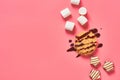 Sweet thin waffles with chocolate cream near marshmallow and candies on pink background