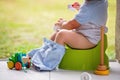 Sweet toddler boy, sitting on potty on a back porch in a holiday resort patio