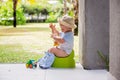 Sweet toddler boy, sitting on potty on a back porch in a holiday resort patio